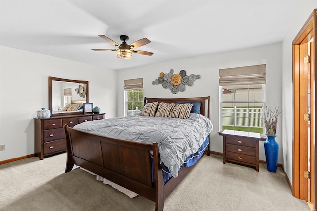 bedroom featuring light colored carpet, baseboards, and a ceiling fan