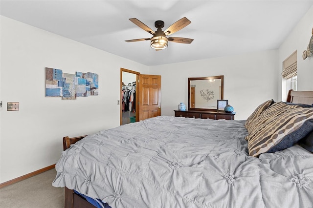 carpeted bedroom featuring ceiling fan, baseboards, and a walk in closet