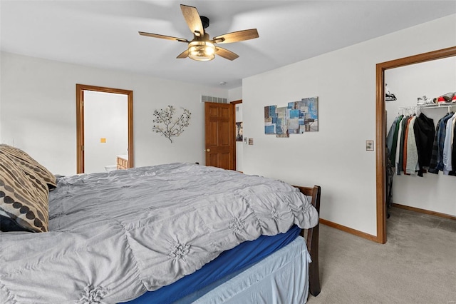 bedroom featuring a spacious closet, light carpet, a closet, baseboards, and ceiling fan