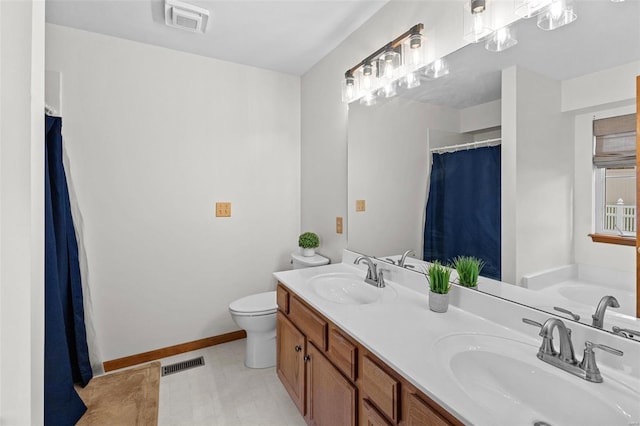 bathroom with toilet, double vanity, and baseboards