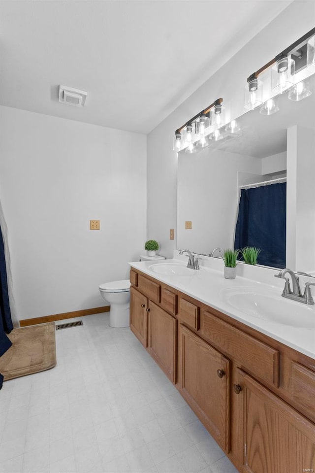 full bathroom with toilet, double vanity, and baseboards
