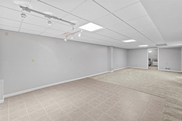 finished basement with carpet flooring, a paneled ceiling, and baseboards