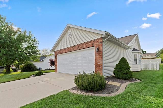 view of side of home with brick siding, a garage, concrete driveway, and a yard