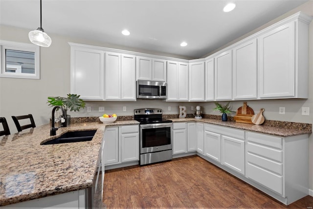 kitchen with recessed lighting, white cabinetry, light stone counters, a sink, and appliances with stainless steel finishes