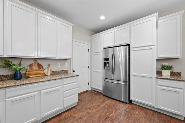 kitchen featuring dark wood-style flooring, stainless steel refrigerator with ice dispenser, recessed lighting, white cabinets, and light stone counters