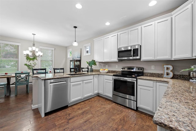 kitchen featuring white cabinets, a peninsula, appliances with stainless steel finishes, and dark wood-style floors