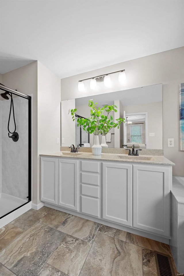 bathroom featuring a sink, a stall shower, and double vanity