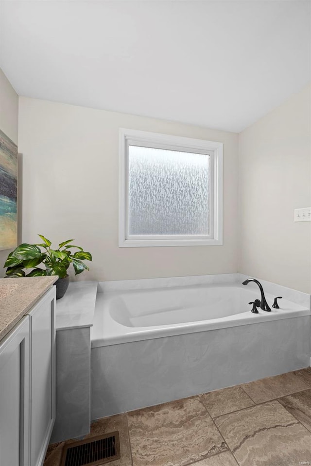full bathroom featuring visible vents, a garden tub, and vanity