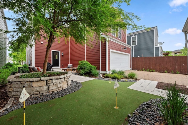 view of yard with fence, an attached garage, and driveway