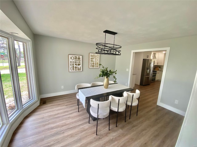 dining area with baseboards, wood finished floors, and plenty of natural light