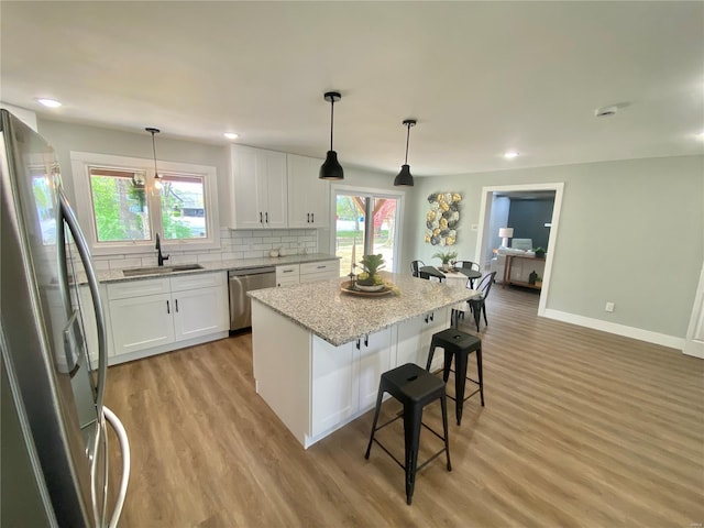 kitchen featuring white cabinets, stainless steel appliances, light wood-style flooring, and a sink