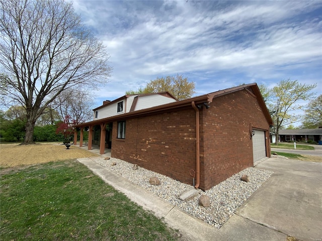 view of home's exterior featuring driveway, a chimney, a garage, brick siding, and a yard