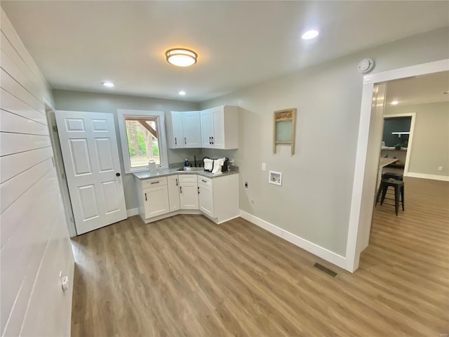 kitchen featuring baseboards, light wood finished floors, and visible vents