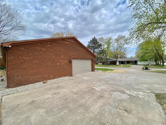 view of side of home with concrete driveway, brick siding, and a garage