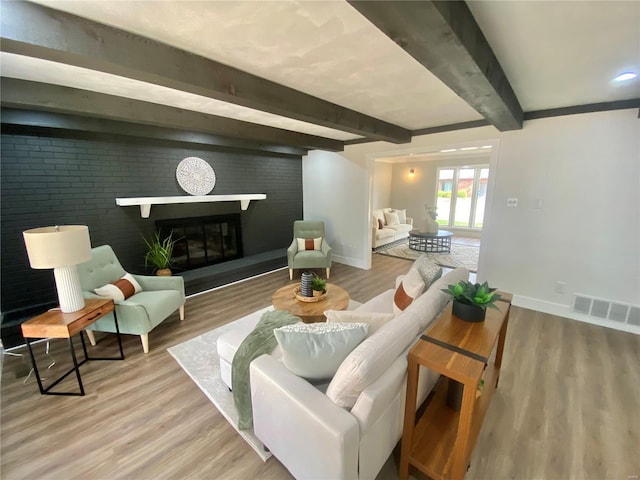living room featuring beamed ceiling, wood finished floors, visible vents, and baseboards