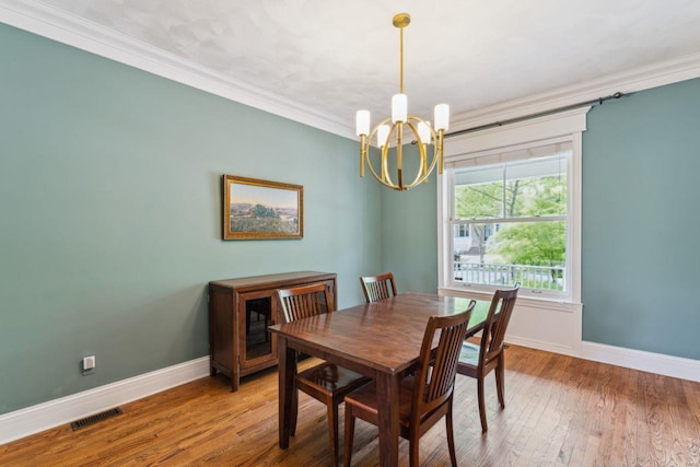 dining area featuring an inviting chandelier, wood finished floors, crown molding, and baseboards