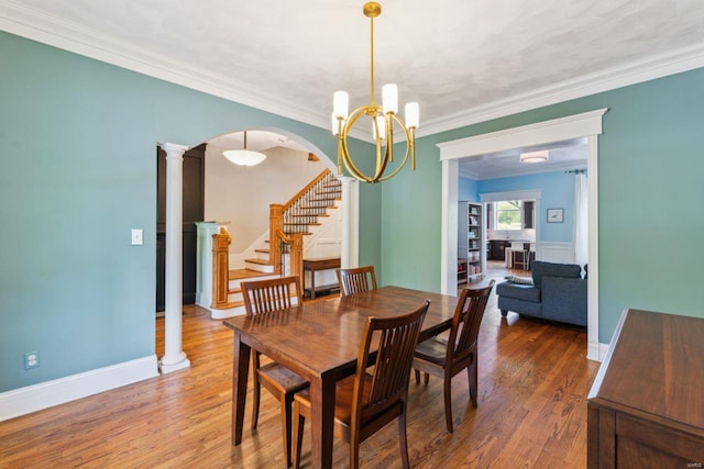 dining space featuring stairway, wood finished floors, an inviting chandelier, and crown molding