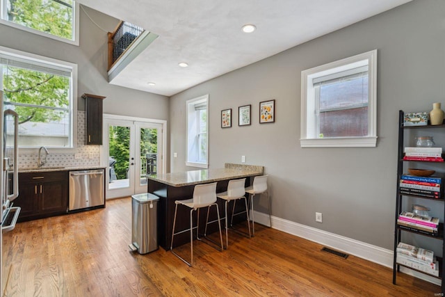 kitchen featuring visible vents, light stone counters, a peninsula, stainless steel dishwasher, and french doors