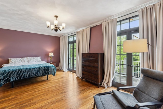 bedroom featuring wood finished floors, a notable chandelier, access to exterior, and multiple windows