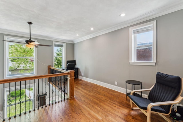 living area featuring an upstairs landing, baseboards, ornamental molding, wood finished floors, and a ceiling fan