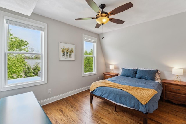 bedroom with a ceiling fan, multiple windows, wood finished floors, and baseboards