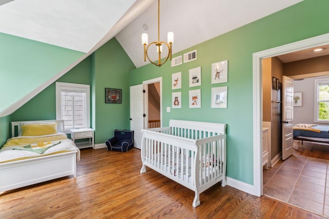 bedroom featuring visible vents, wood finished floors, a notable chandelier, and lofted ceiling