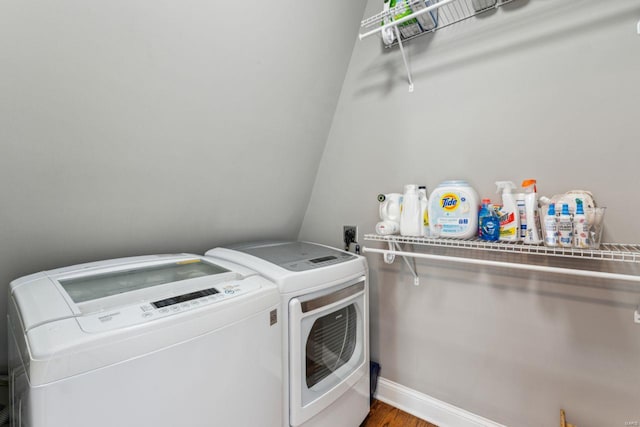 washroom with wood finished floors, baseboards, laundry area, and washing machine and dryer