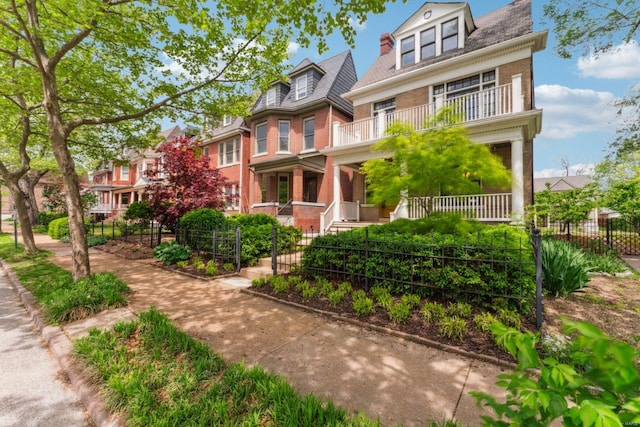 view of front of property featuring a porch, fence private yard, a balcony, and brick siding
