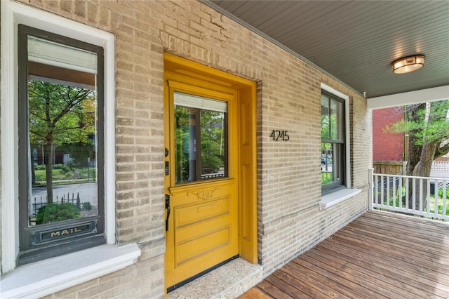 property entrance featuring covered porch and brick siding