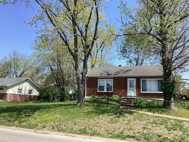 view of front facade featuring fence, a front lawn, and brick siding