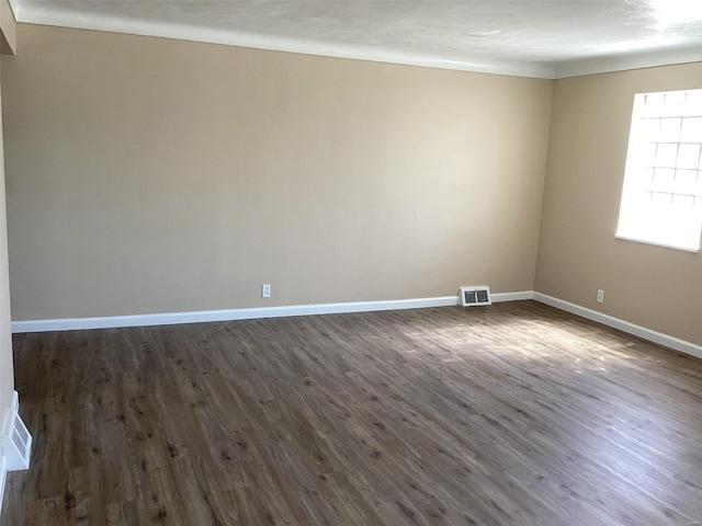 spare room featuring baseboards, visible vents, and dark wood-type flooring