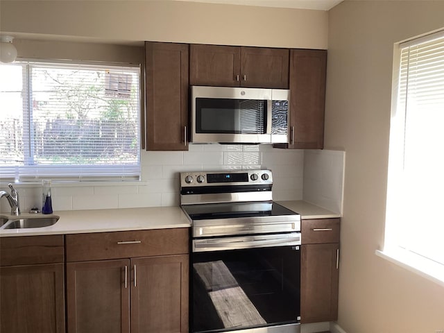 kitchen featuring backsplash, appliances with stainless steel finishes, a sink, and light countertops