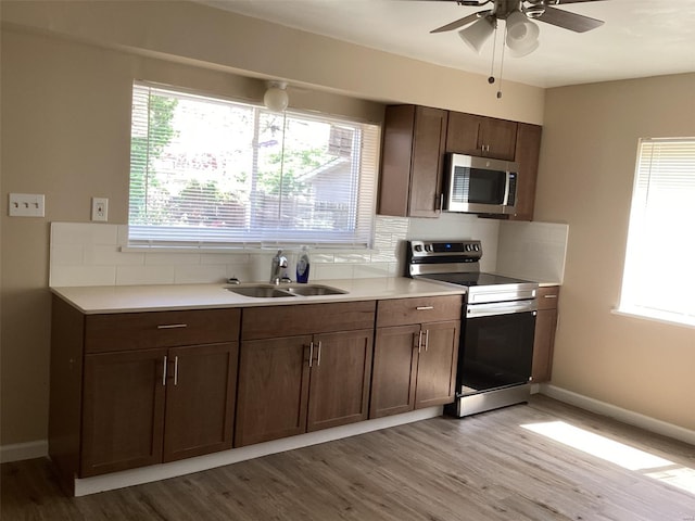kitchen featuring stainless steel appliances, light wood-style flooring, a sink, tasteful backsplash, and plenty of natural light