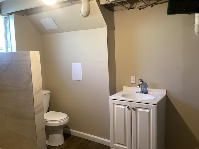 bathroom with lofted ceiling, wood finished floors, vanity, and toilet