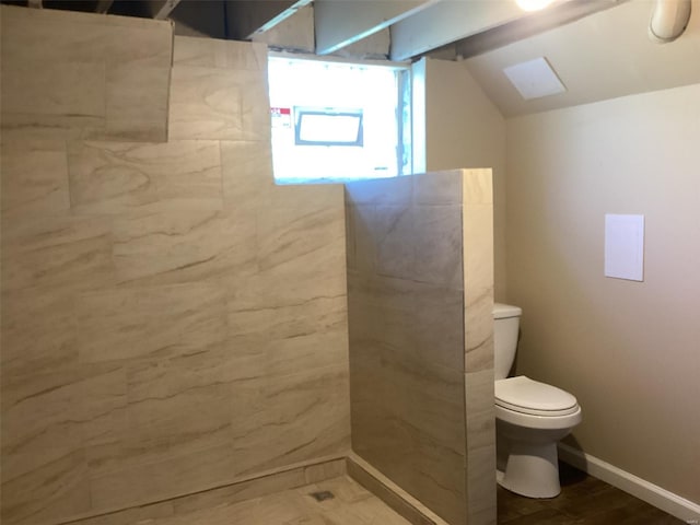 full bath with baseboards, vaulted ceiling, toilet, and tiled shower