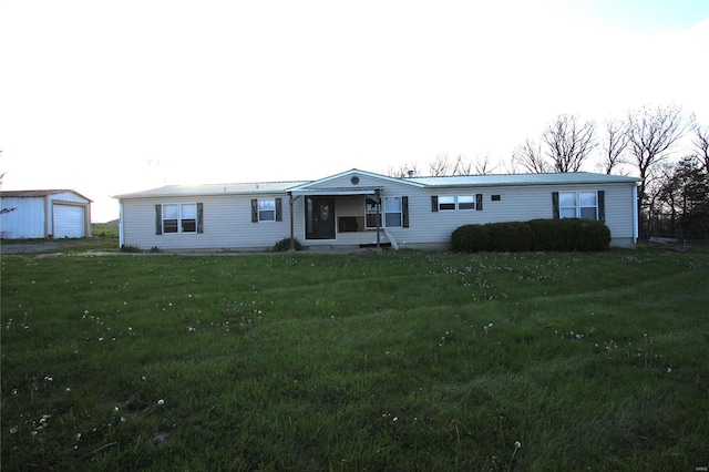 view of front of house featuring an outbuilding, a detached garage, and a front lawn