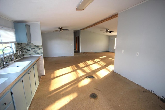 kitchen featuring ceiling fan, blue cabinets, light countertops, a sink, and backsplash