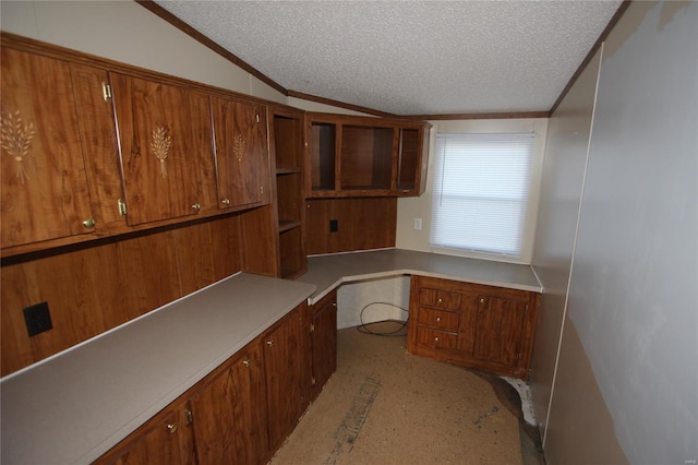 unfurnished office with built in desk, a textured ceiling, crown molding, and vaulted ceiling