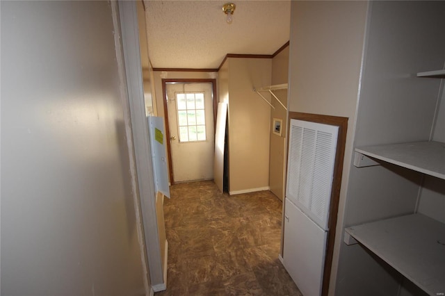 corridor with crown molding, baseboards, a heating unit, and a textured ceiling