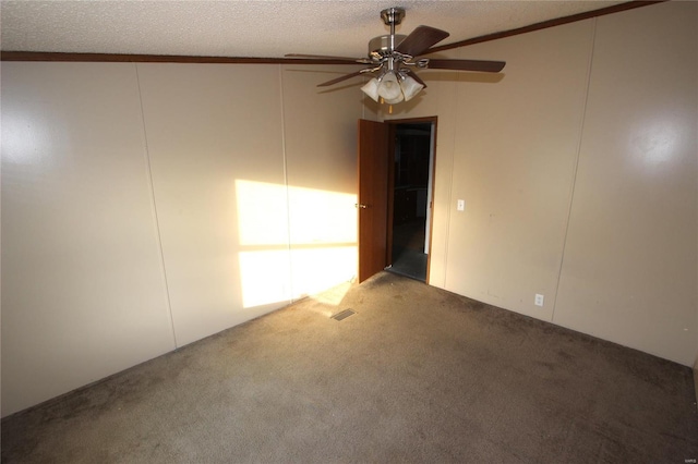 spare room featuring ceiling fan, a textured ceiling, ornamental molding, visible vents, and carpet flooring
