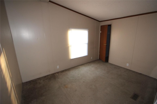 carpeted empty room with a textured ceiling, visible vents, ornamental molding, and lofted ceiling