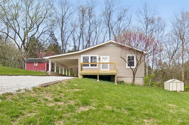 rear view of property with a shed, driveway, an outbuilding, a lawn, and a deck