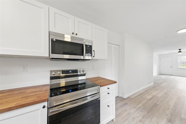 kitchen featuring white cabinets, butcher block counters, baseboards, light wood-style flooring, and appliances with stainless steel finishes