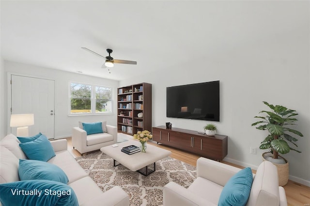 living area featuring baseboards, a ceiling fan, and wood finished floors