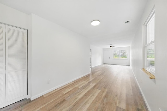unfurnished living room featuring light wood-type flooring, visible vents, baseboards, and ceiling fan