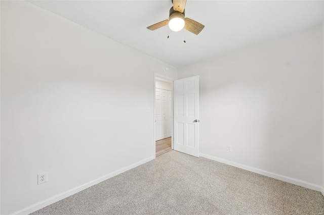 spare room featuring light colored carpet, ceiling fan, and baseboards