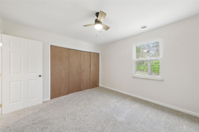 unfurnished bedroom with a closet, visible vents, carpet flooring, and baseboards