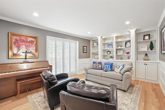 living room with light wood finished floors, crown molding, a wainscoted wall, a decorative wall, and ornate columns