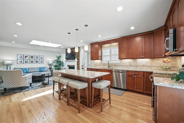 kitchen with open floor plan, a sink, stainless steel appliances, and light wood-type flooring