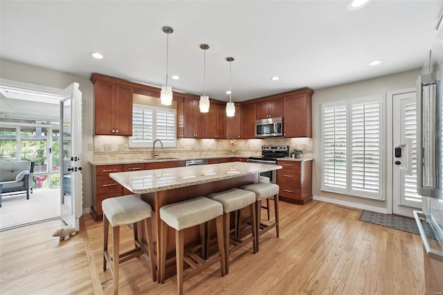 kitchen with a wealth of natural light, stainless steel appliances, light wood-type flooring, and a sink